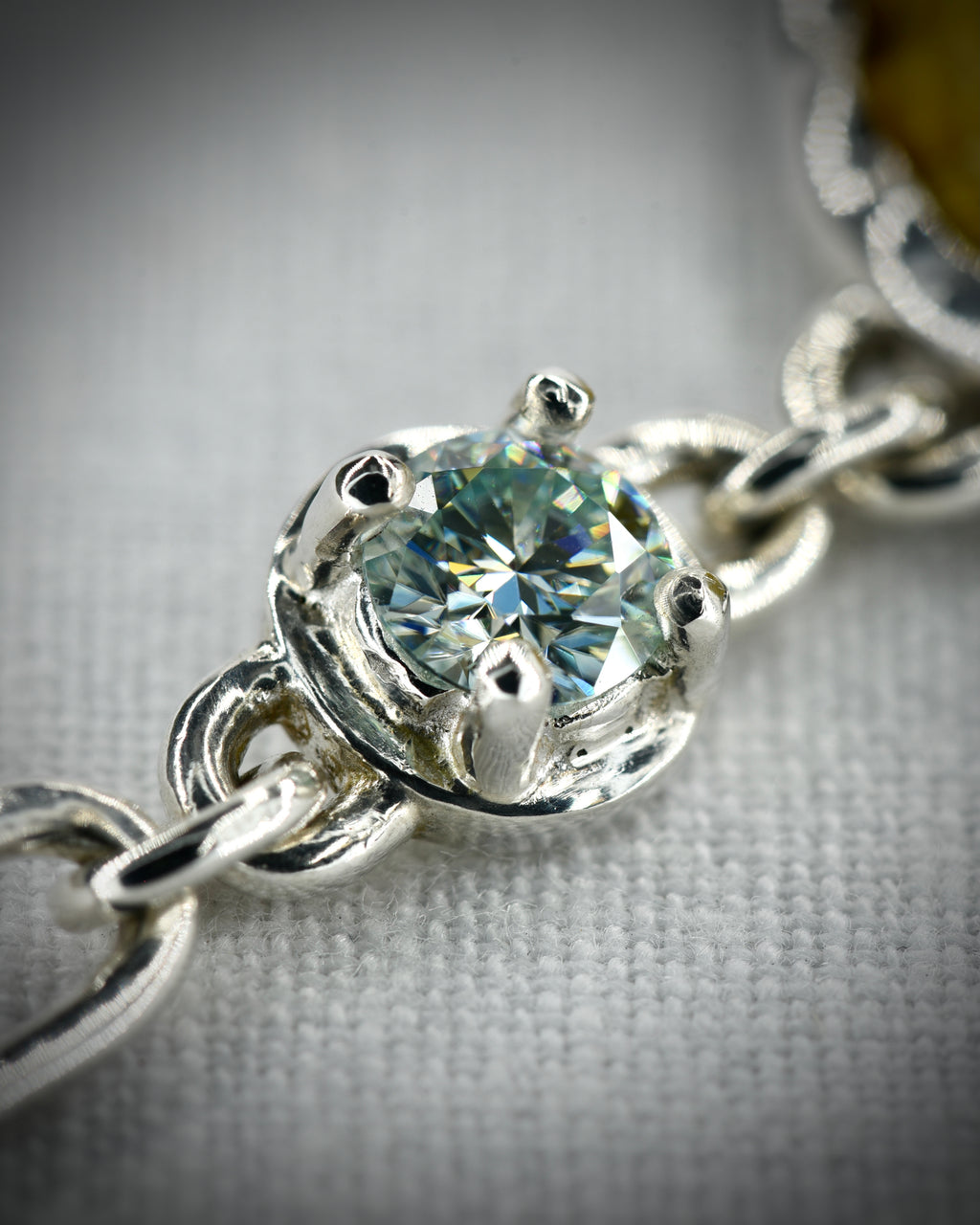 Close view of the sterling silver prong set moissanite connector and chain links
