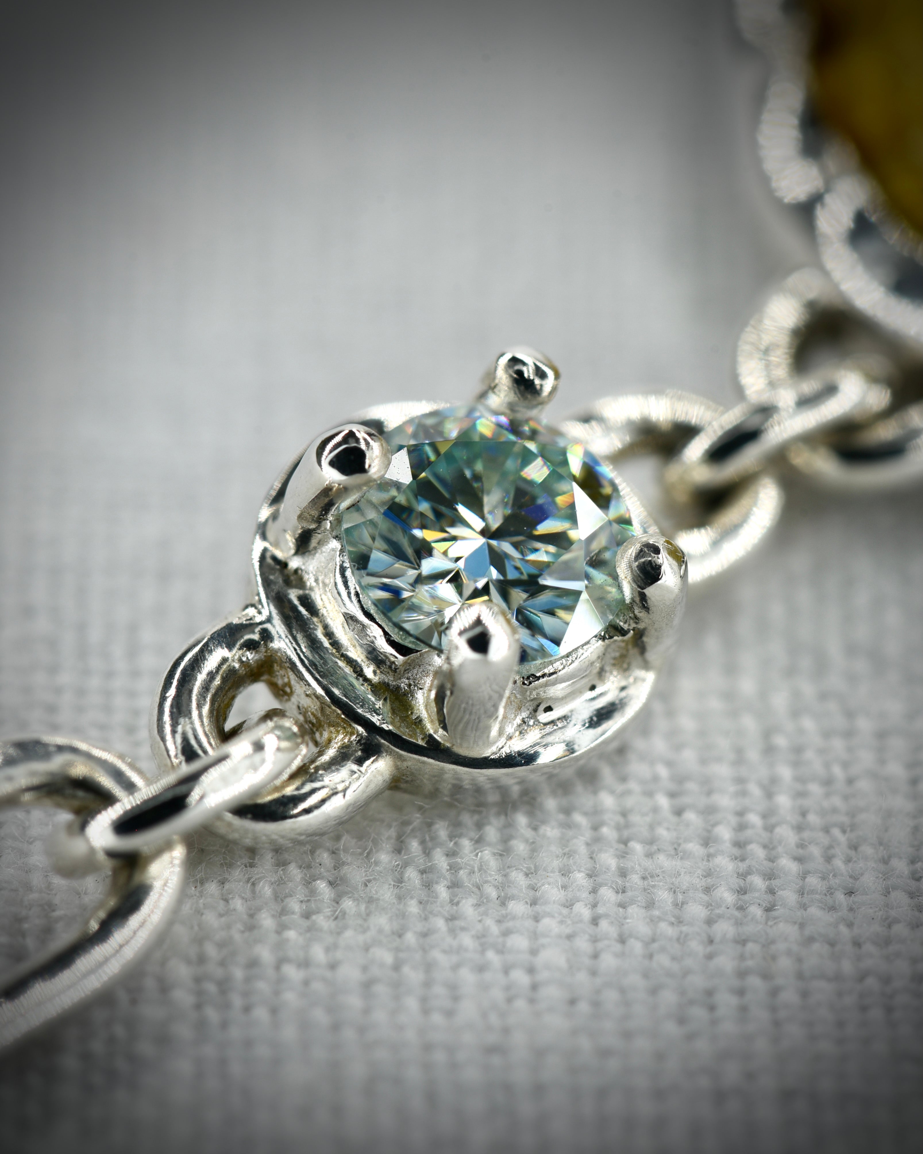 Close view of the sterling silver prong set moissanite connector and chain links
