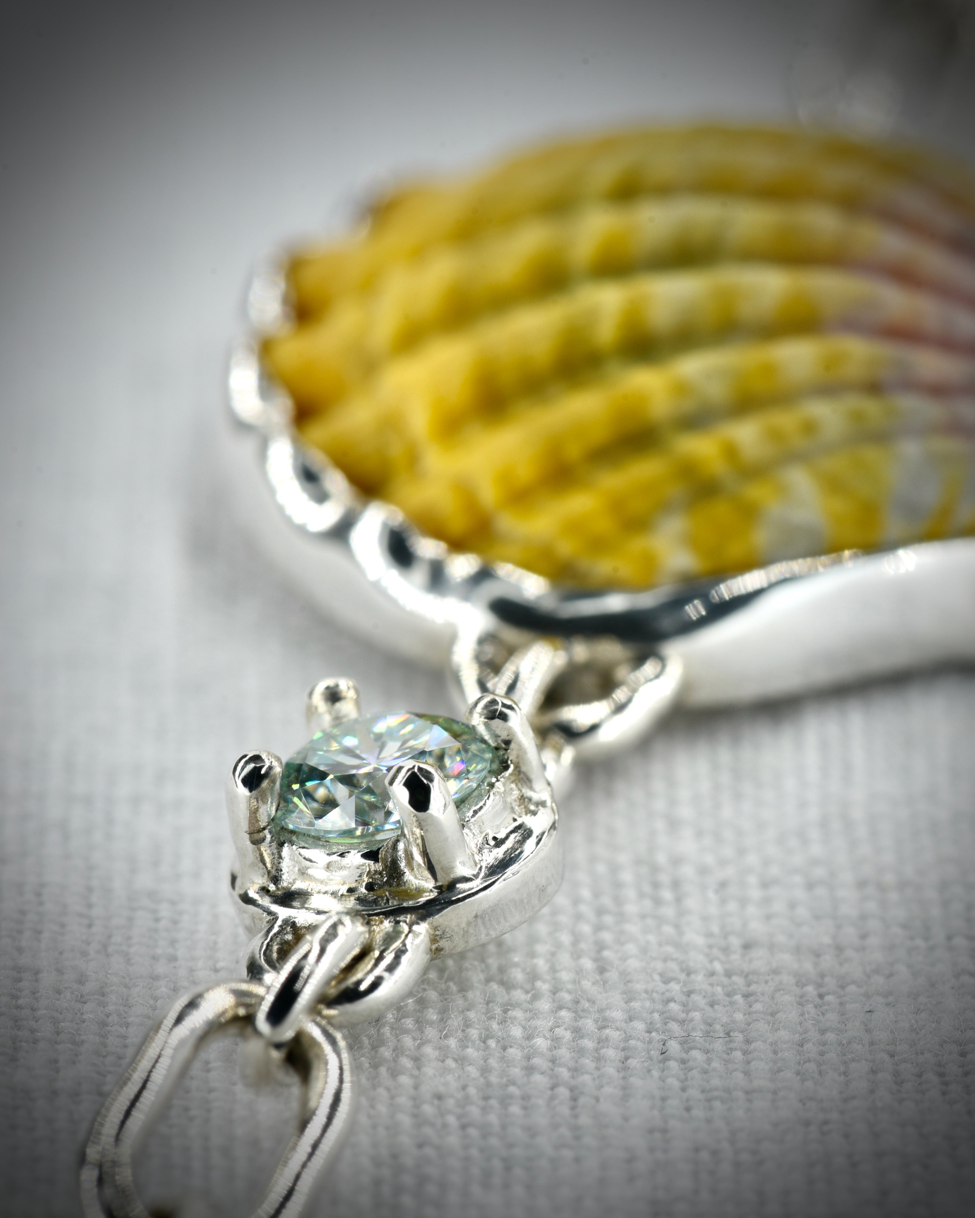 Close view of the sunrise shell setting and moissanite accent on the sterling silver bracelet