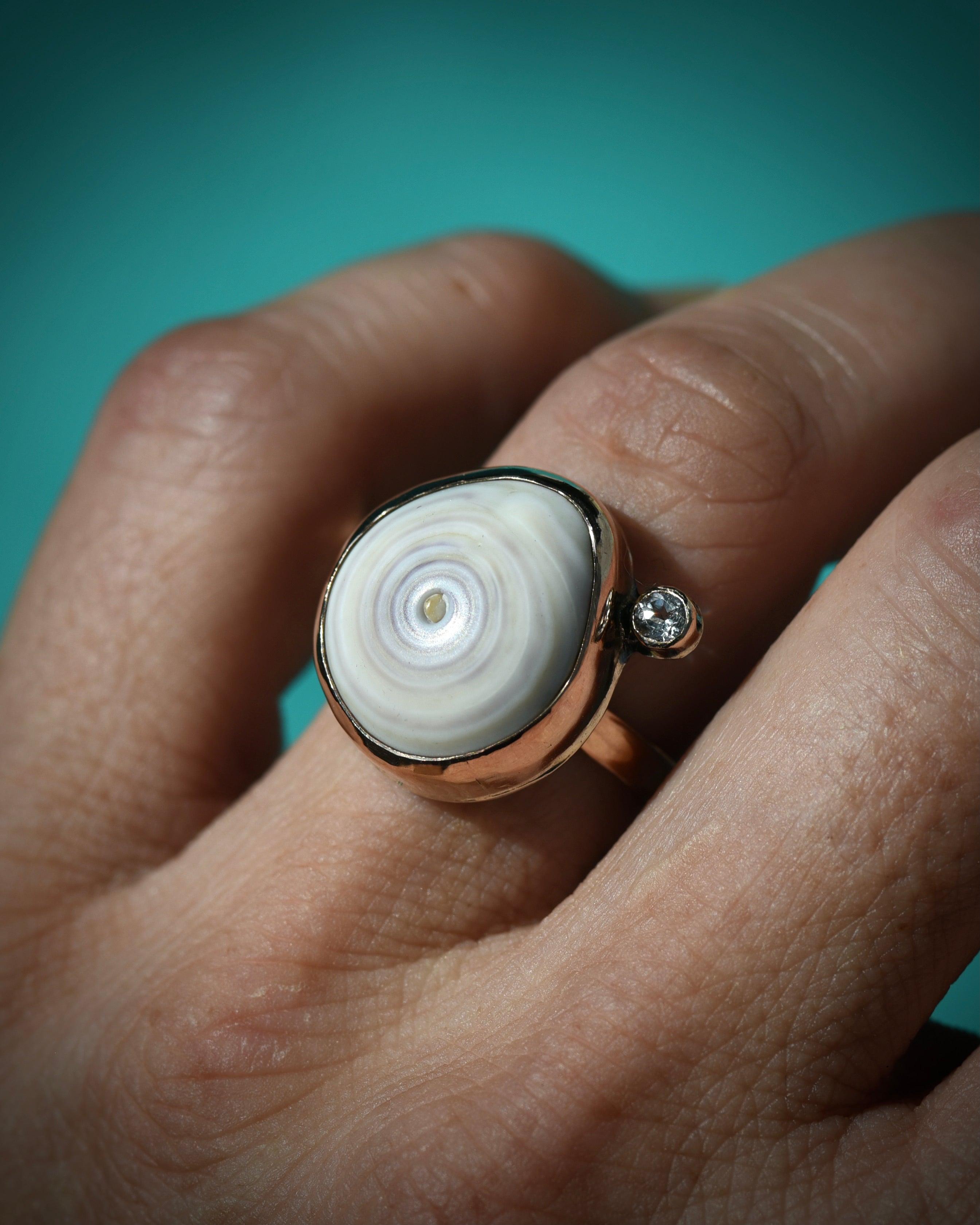 Pale purple and white swirl Hawaiian puka shell ring worn on the finger, showing the natural concentric shell pattern
