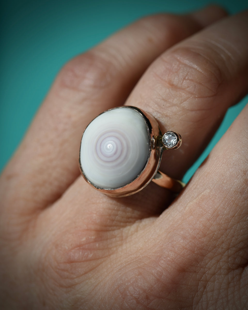 White and light pink Hawaiian puka shell ring worn on the finger, showing the soft concentric shell pattern
