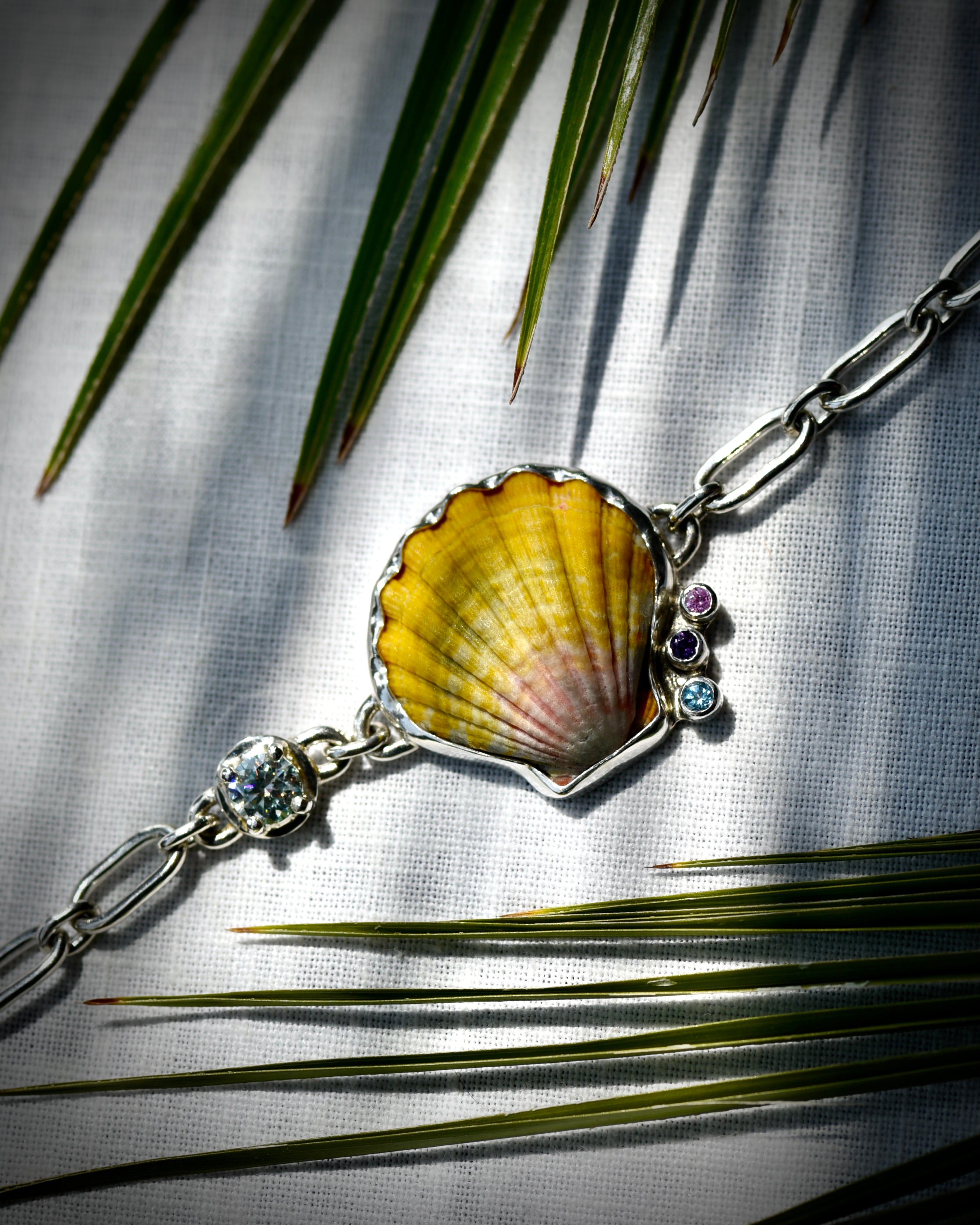 Hawaiian sunrise shell bracelet displayed flat beneath palm leaves