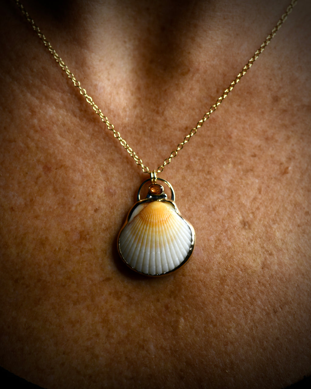 Orange and cream scallop shell pendant necklace worn on a delicate chain