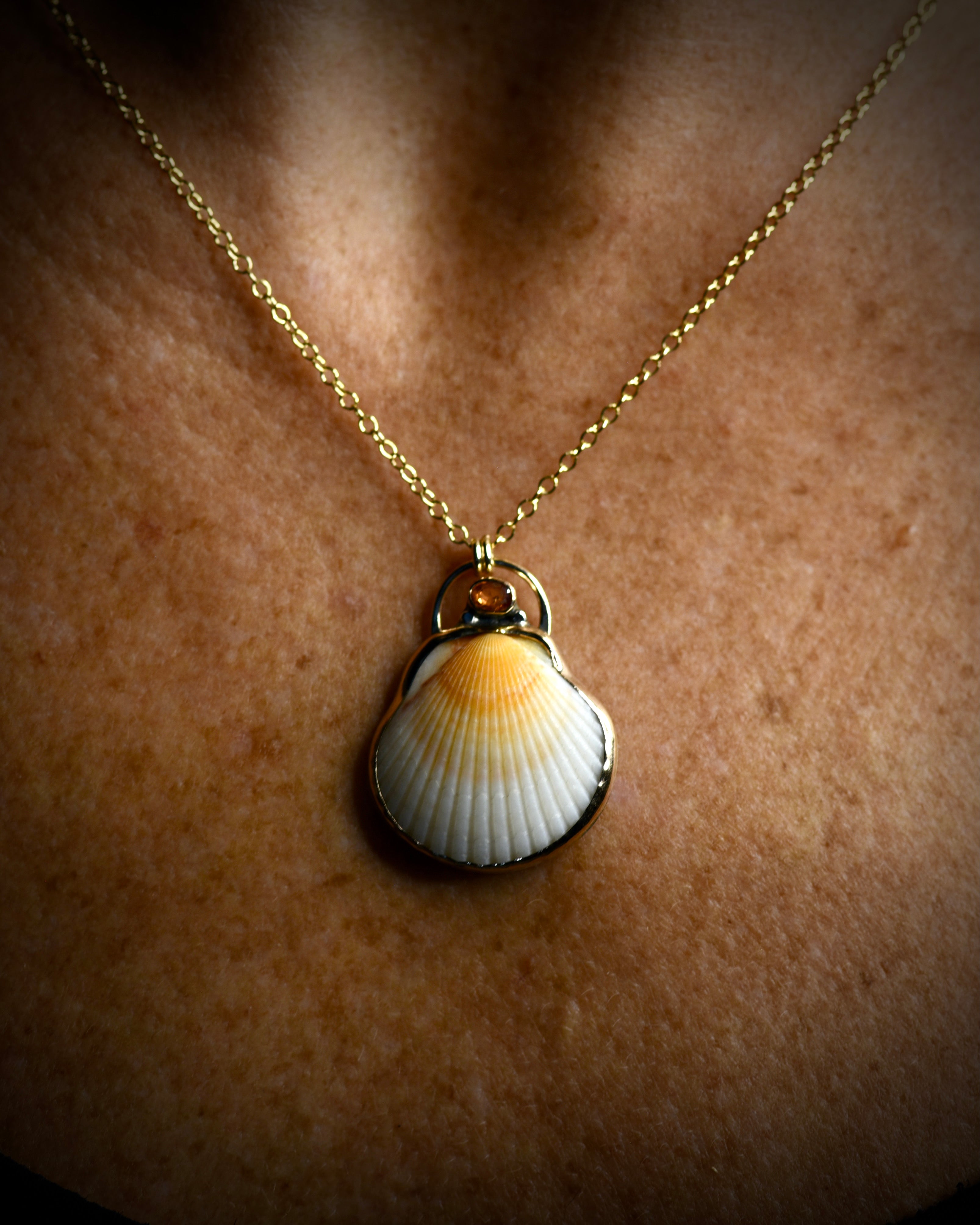 Orange and cream scallop shell pendant necklace worn on a delicate chain