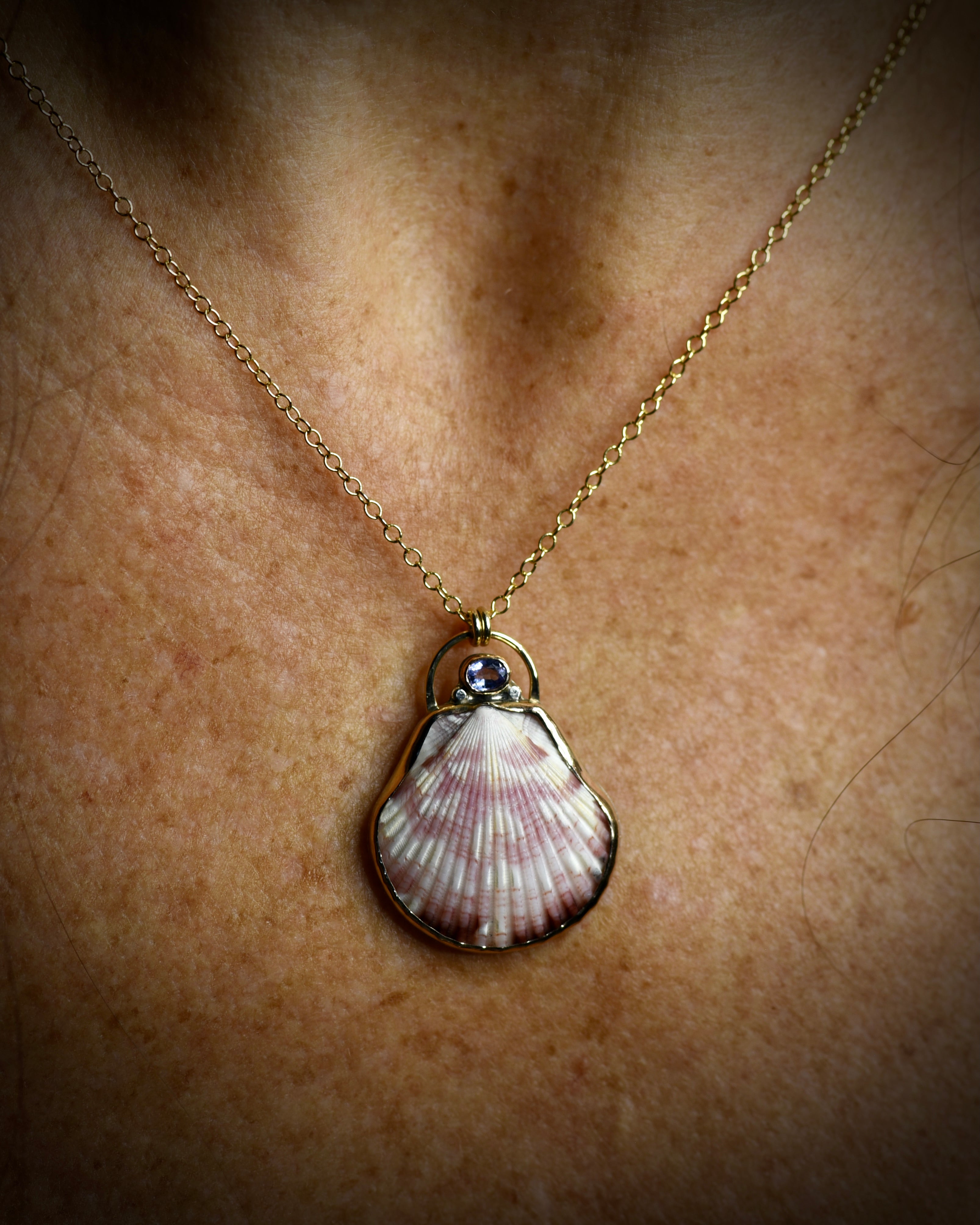 Pink patterned scallop shell pendant necklace worn on a delicate chain