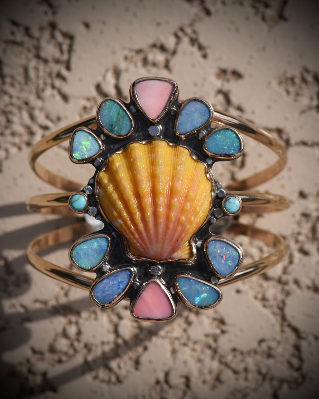 Front view of Reef Riot cuff with pink and yellow Hawaiian sunrise shell surrounded by opal, turquoise, and pink conch