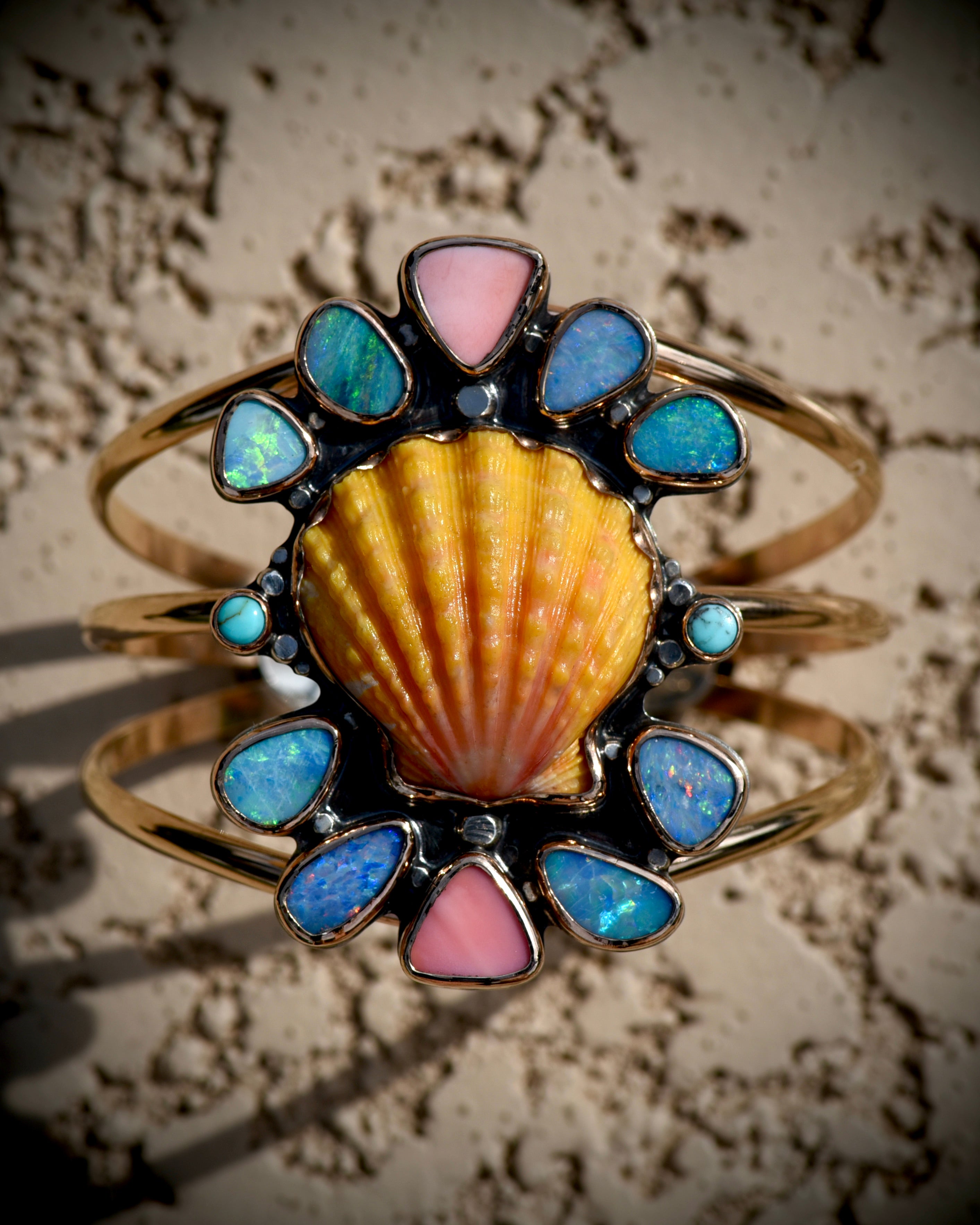 Angled view of Reef Riot statement cuff highlighting the Hawaiian sunrise shell, Australian opals, Kingman turquoise, and pink conch

