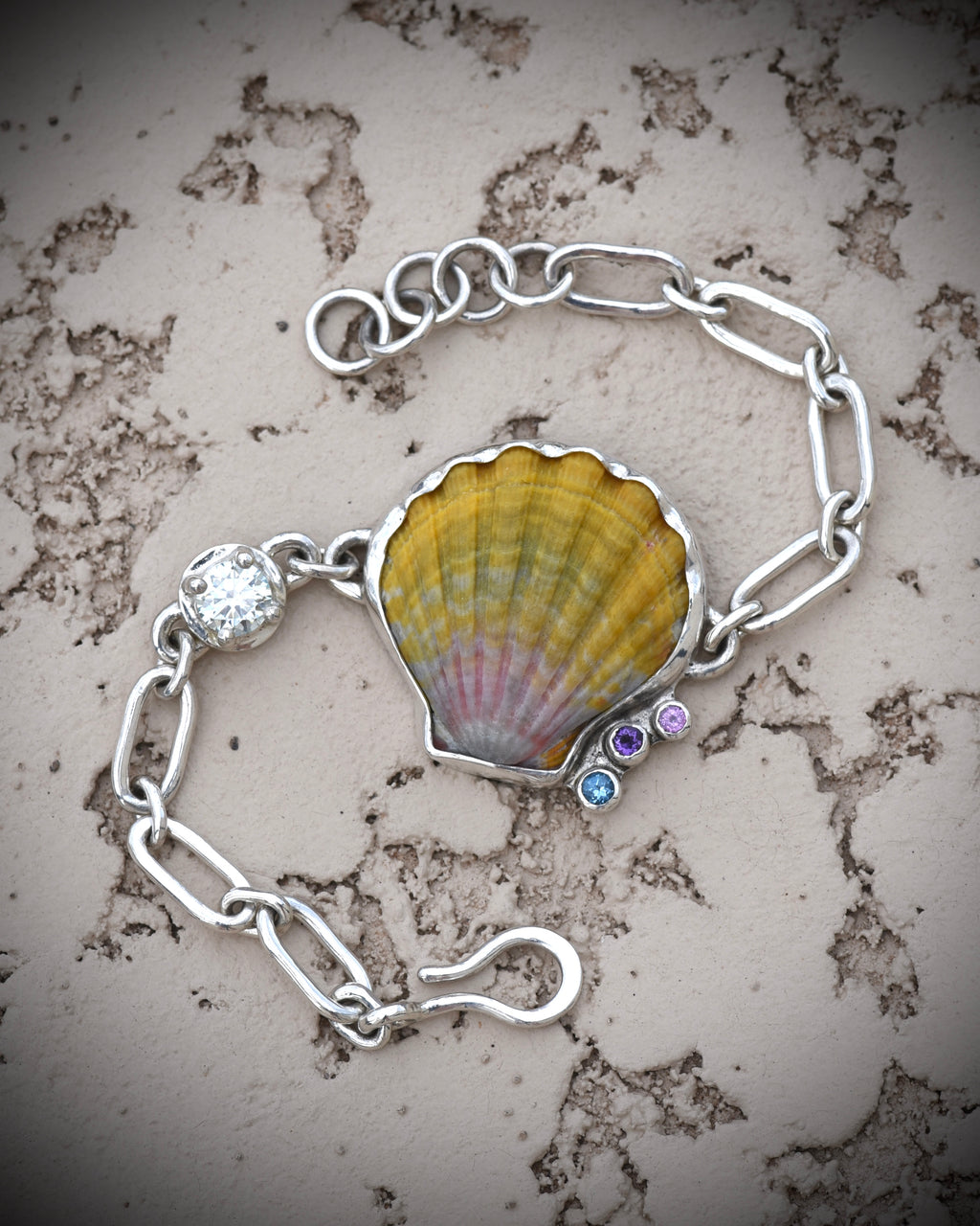 Full view of the adjustable sunrise shell bracelet showing the chain, gemstone accents, and shell centerpiece

