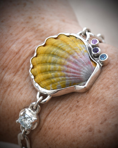 Hawaiian sunrise shell bracelet worn on the wrist, showing the golden shell and gemstone details