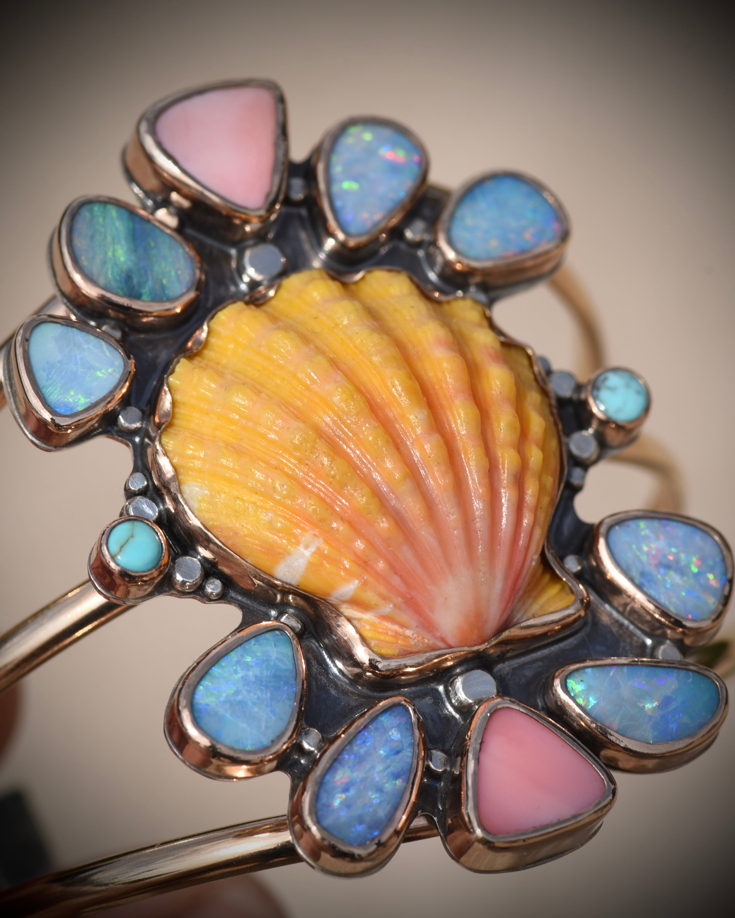 Close view of Reef Riot cuff highlighting the Australian opals, Kingman turquoise, pink conch, and sunrise shell centerpiece
